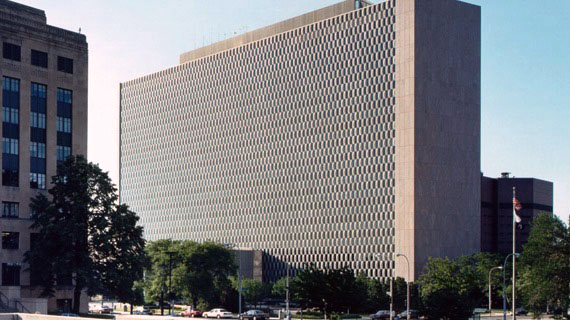A multi-story beige building with alternating checker-board appearance on exterior sides.