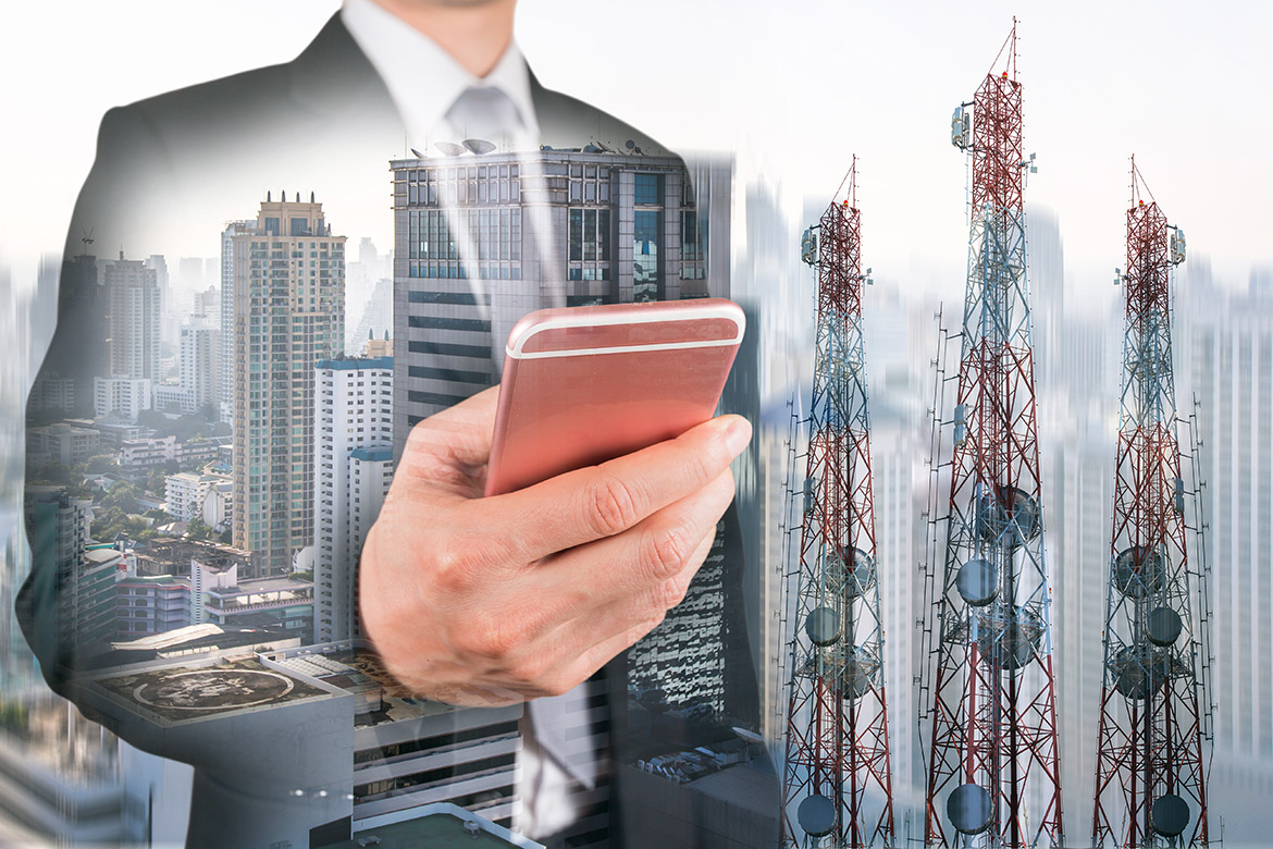 Person holding mobile phone with cityscape and towers in the background