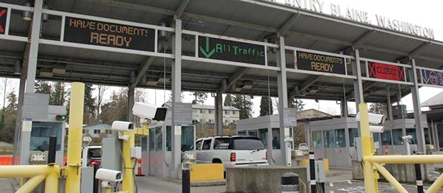 Canopy covering booths and driving lanes, with signs indicating Have documents ready, All traffic, and Closed, and yellow guard rails in the foreground