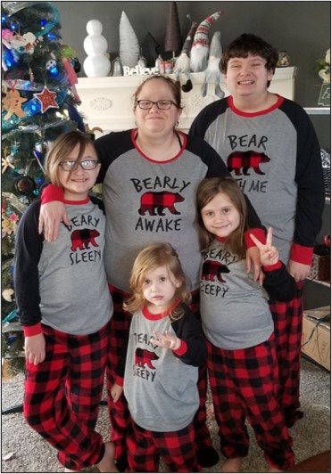Cara Fowler and her four children post in front of a Christmas tree wearing matching outfits.