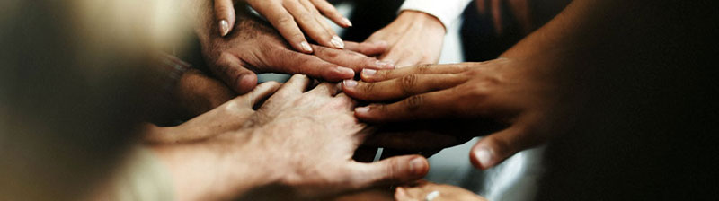 Close up of many multicultural hands coming together in the middle of a circle
