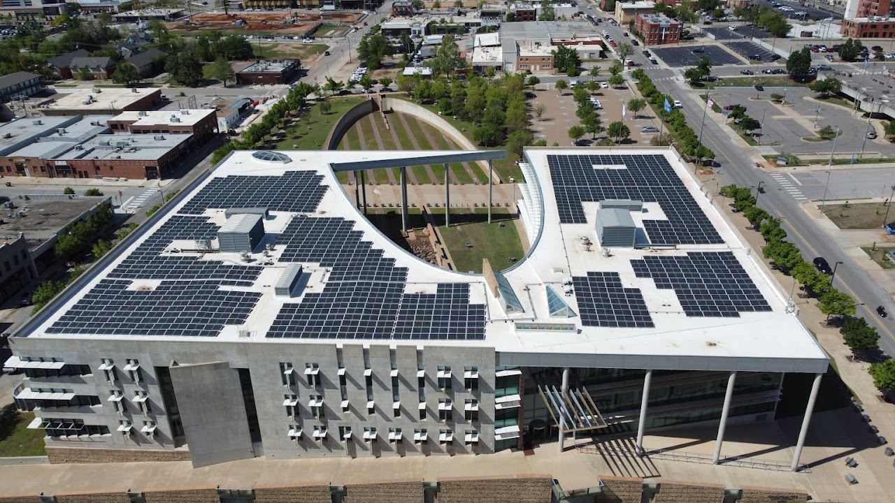 Aerial view of the Oklahoma City Federal building with a solar panel-covered roof, surrounded by urban landscape and green spaces.