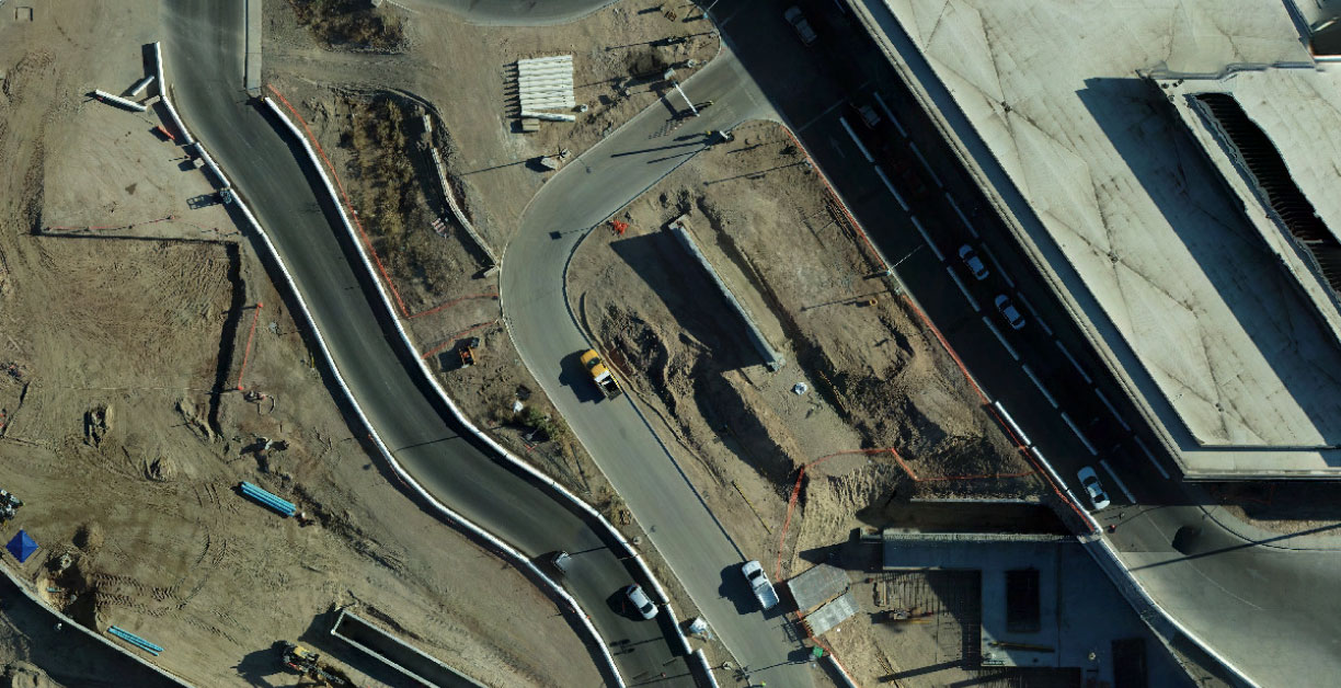 Overhead view of construction area with curved lanes and roads, with a building to the right
