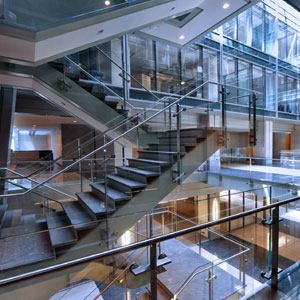 Photo of a modern, open stairwell with glass railings in the center of an office building atrium.
