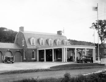 a building with a car port in front of it and a flag pole to the right