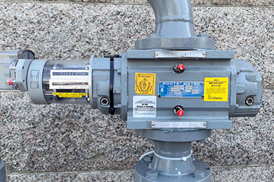 Gray pipe with meter configuration with red lights and yellow labels