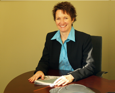 Mary Ruwwe, FAS Region 6 Commissioner - sitting at desk holding book.