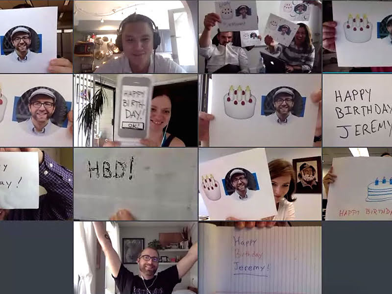 A screenshot of a virtual meeting with people holding signs with birthday cakes