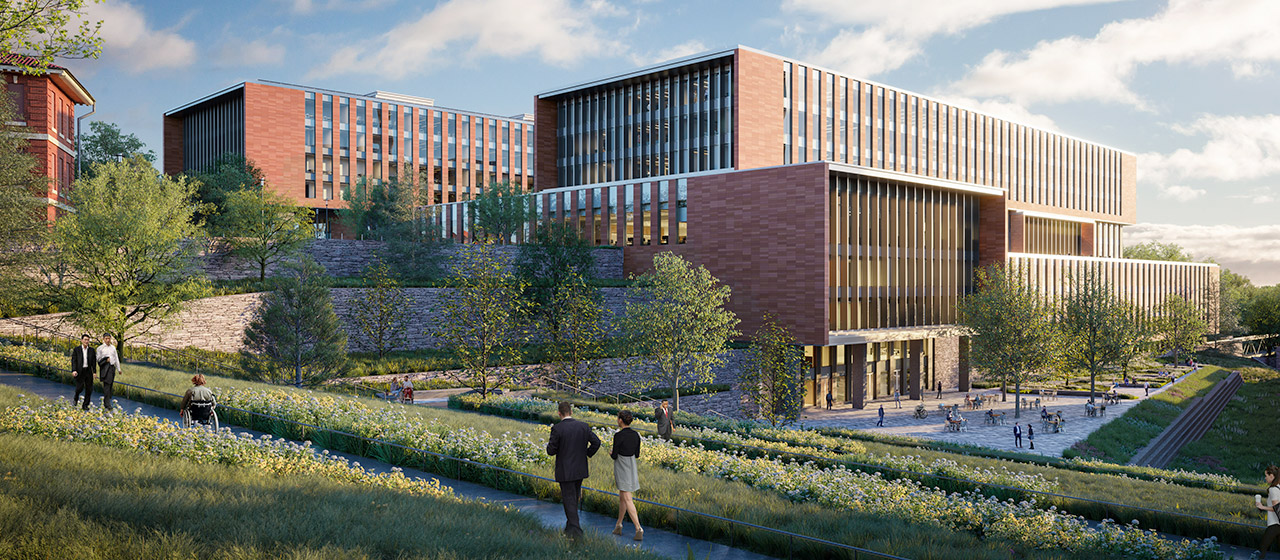 Red brick split-level building with stone retaining walls and trees and a trail