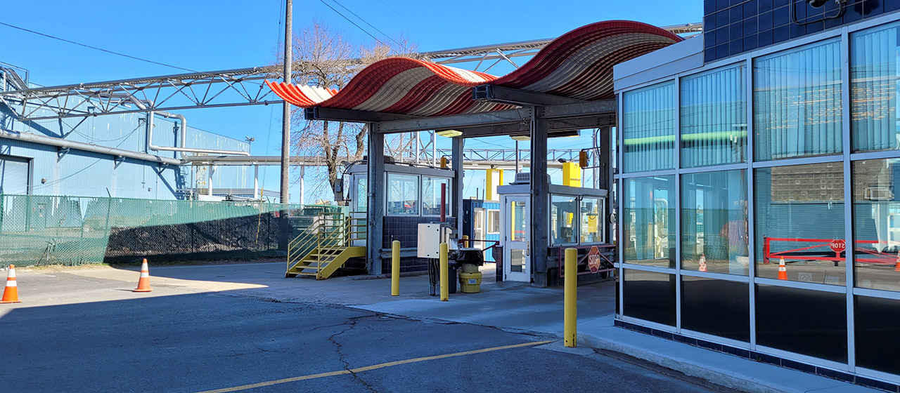 Red and white wavy cover over two drive-through lanes and booths, next to a glass-windowed building