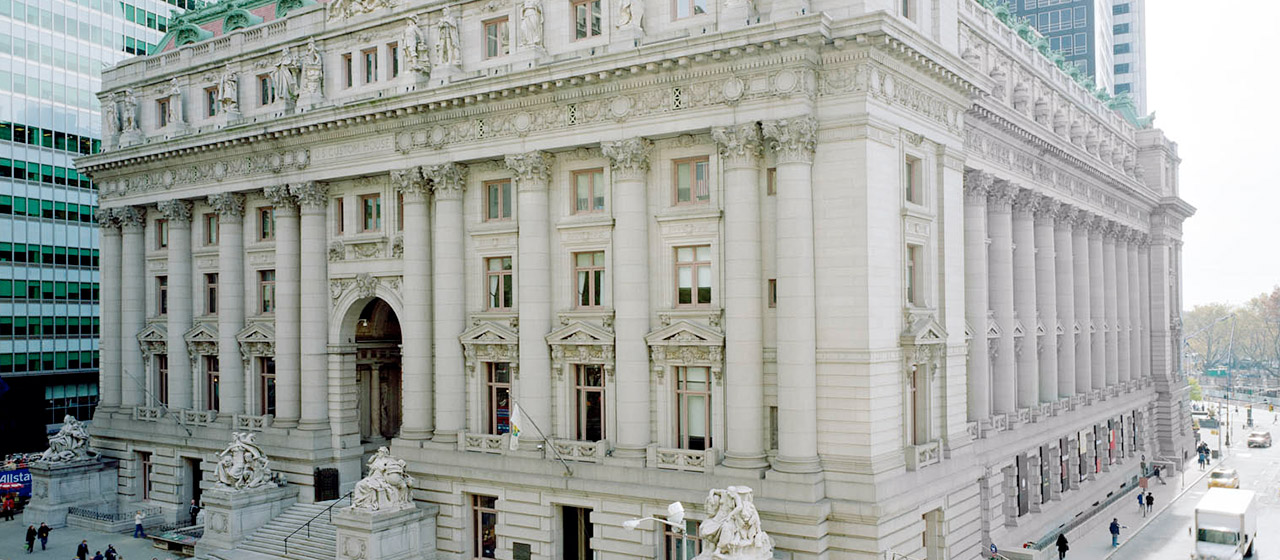 Angled view of a grand, ornate multi-level building with columns and statues around the entry