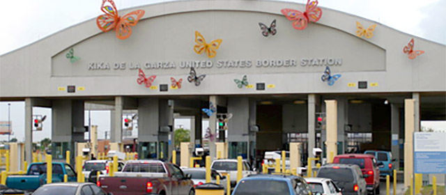 Large canopy with engraved text Kika de la Garza United States Border Station with several lanes of cars in line under it