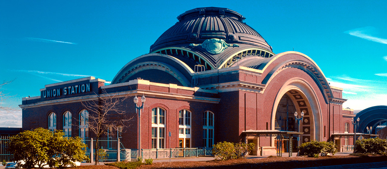 Red brick building with a sign on one side, Union Station. It has a dome in the center, and an arched entrance.