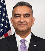 Headshot of Mehul Parekh. Mehul has dark hair and wears a black suit jacket, white shirt, and purple tie.