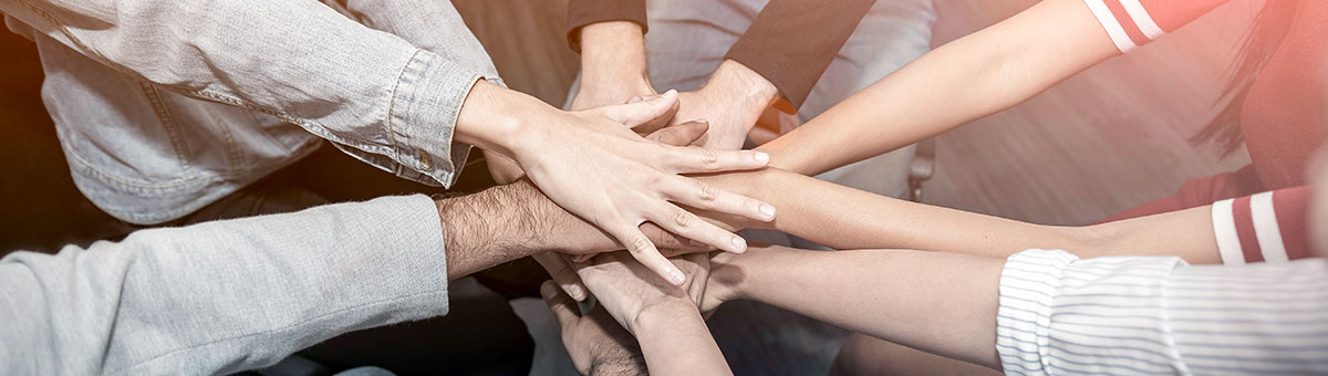 Close up of many hands meeting in the center of a circle of people