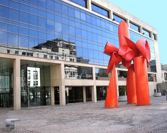 building in the background with red art sculpture in front