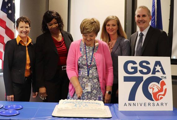 Senior Advisor to the Regional Administrator Judy Dungan (center) cuts the ceremonial cake to celebrate GSA's 70th anniversary