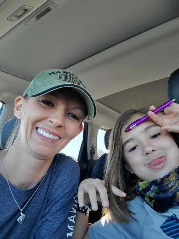 A light-haired woman and a dark-haired young girl pose for a picture inside a vehicle.