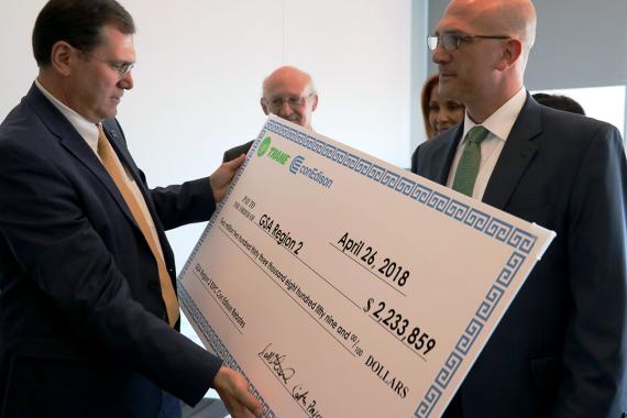 A man examines a large check while others look on.