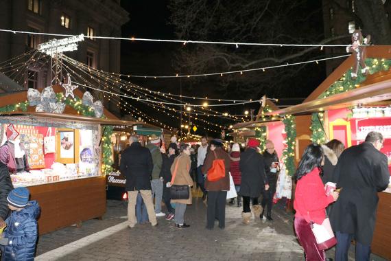 Crowd dressed in warm clothing walking around in a holiday-themed outdoor market