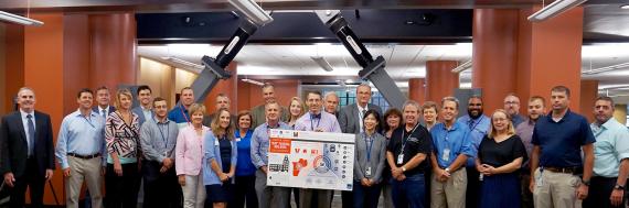 Members of the team that worked on the seismic renovation project stand in front of a viscous damper.