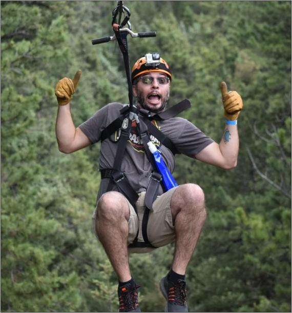 Steven Baker giving a double thumbs-up while ziplining. 