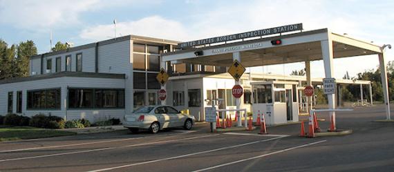 Quarter view of the front of a low white building with two booths next to two lanes