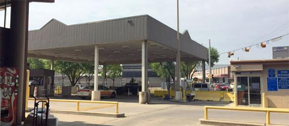 A canopy structure next to a tan building, with several lanes with booths and yellow medians