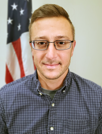 Person with glasses in front of an American flag.
