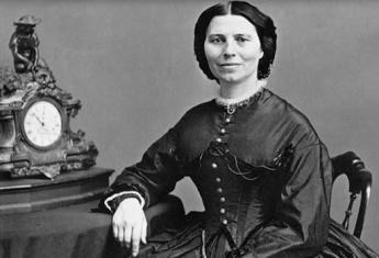 Clara Barton in a dress sitting at a table