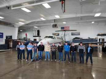 People standing in front of a plane in a hangar