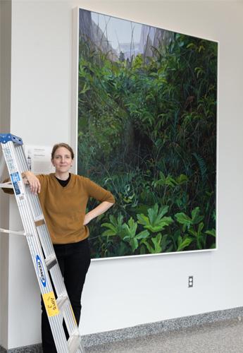 Artist Claire Sherman next to one of her paintings on display at the third floor elevator lobby.