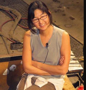 Maya Lin smiling and sitting with her arms crossed