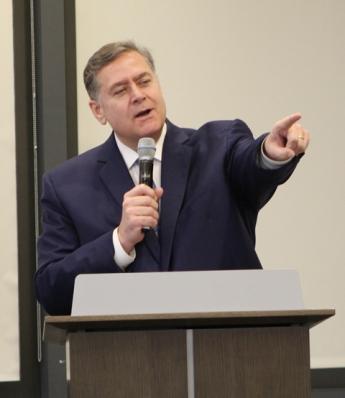Michael Copeland standing behind a podium in GSA&#039;s conference center pointing.