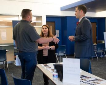 Two men and one woman in business attire standing in office and talking