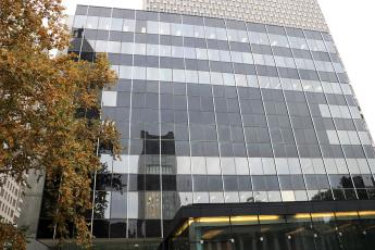 Steel and glass multi-level building with autumn tree to the left and another building behind it