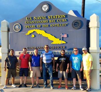 GSA employees pose for a picture in front of a welcome sign at Guantanamo Bay, Cuba