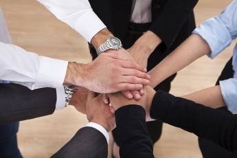 A stock photo of hands on top of one another in a circle