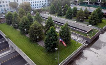 Photo of an intensive green roof at the U.S. Tax Court. It shows a law with tall evergreen trees, with a road going under the building.