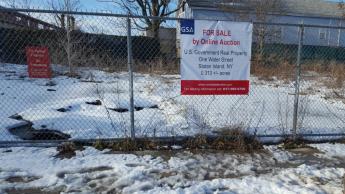 Banner with information attached to a fence giving more information about a vacant parcel of land for sale on Staten Island, New York.