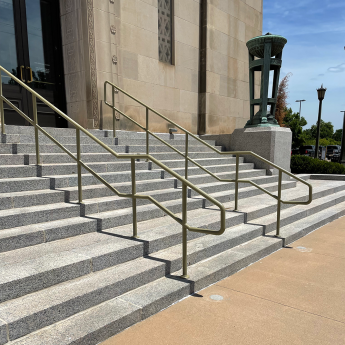 Exterior building steps with two new handrails, slightly curved at bottom step.