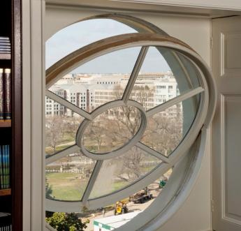 Photo of a circular window in a historic building that is open by tilting the top inward.