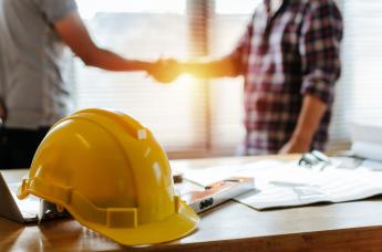 Stock image of two people shaking hands with a hard hat