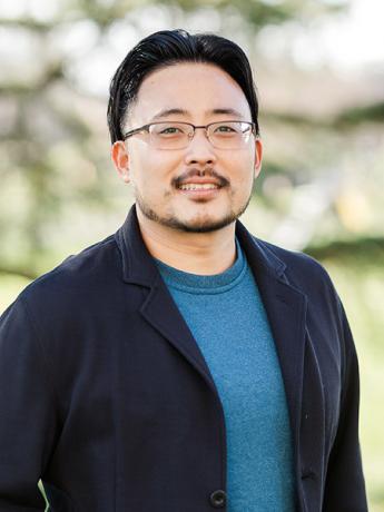 Photo of Daniel Kim, a smiling Asian male wearing eye glasses, standing in front of trees in the background