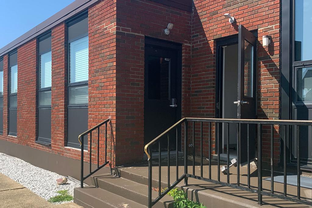 Stairs lead to an exterior door on a red brick building.