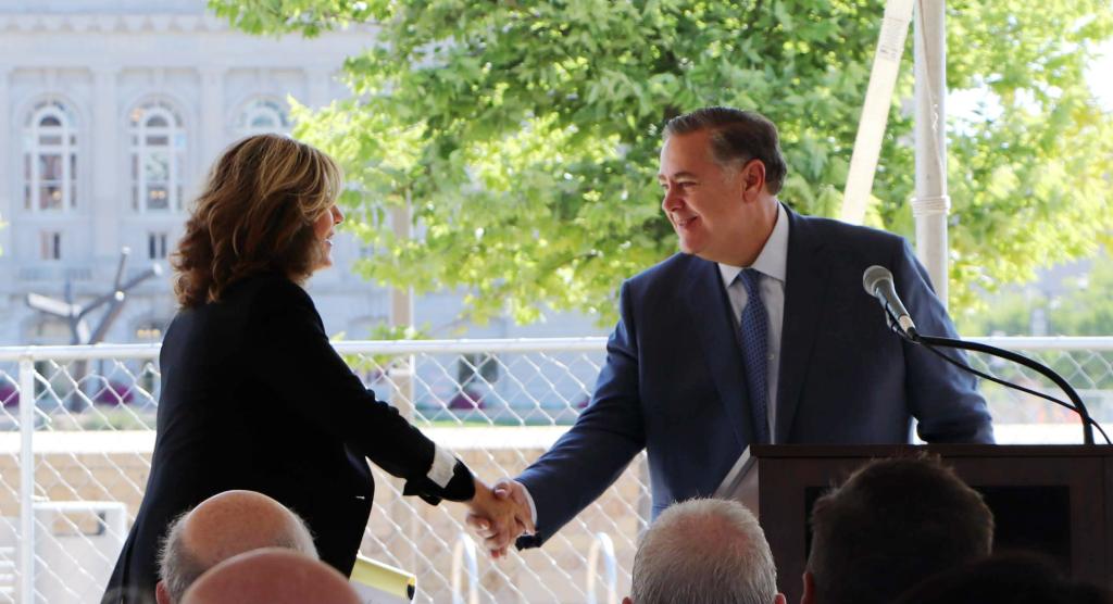Allison Azevedo shakes Michael Copeland's hand on her way to the lectern to deliver her remarks