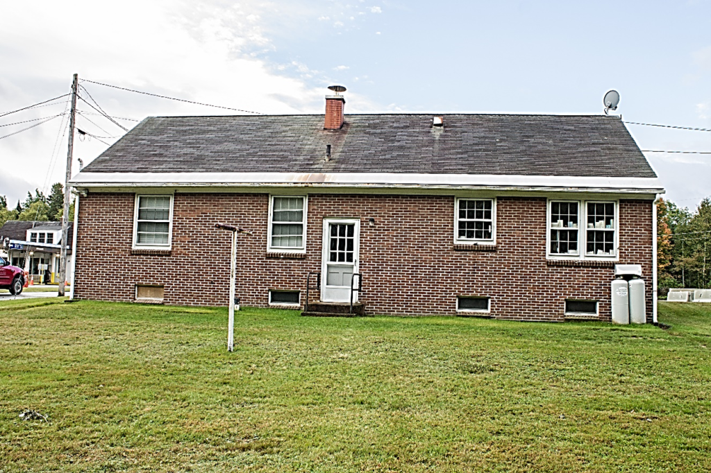 rear shot of one story brick building with 5 windows and a door 