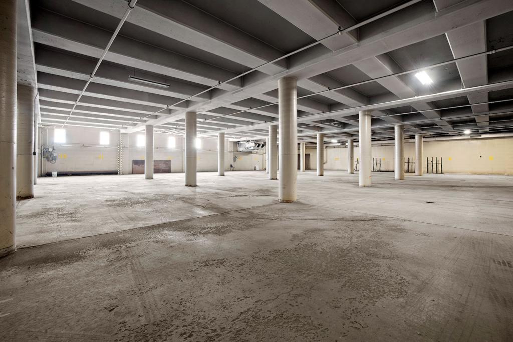 A large empty space with windows, pillars, and concrete floors.