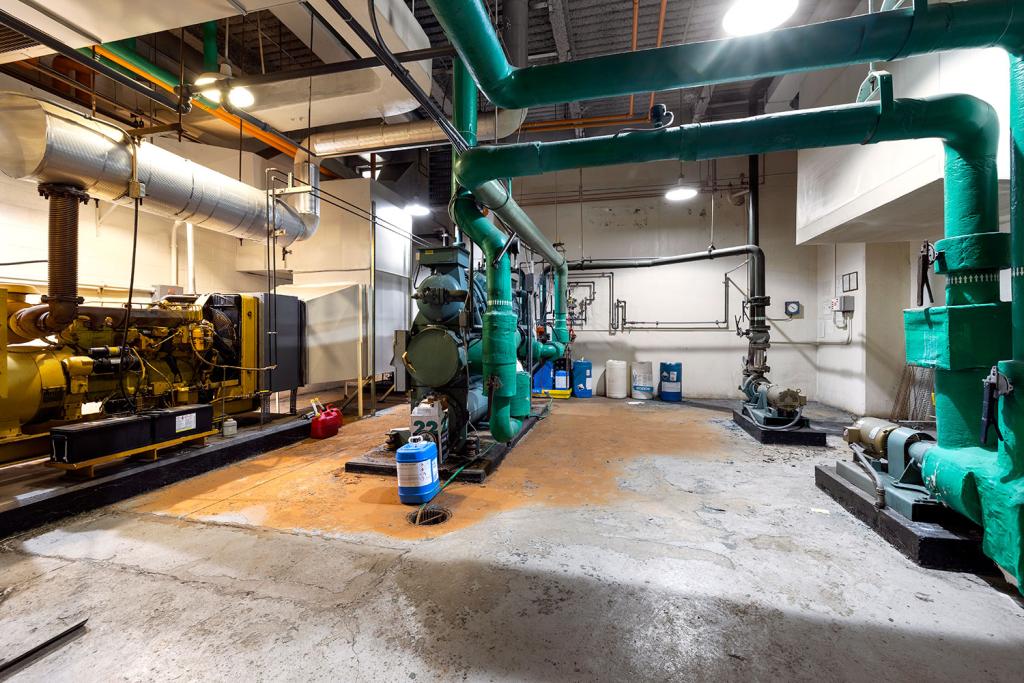 A boiler room with green and yellow pipes and machinery.