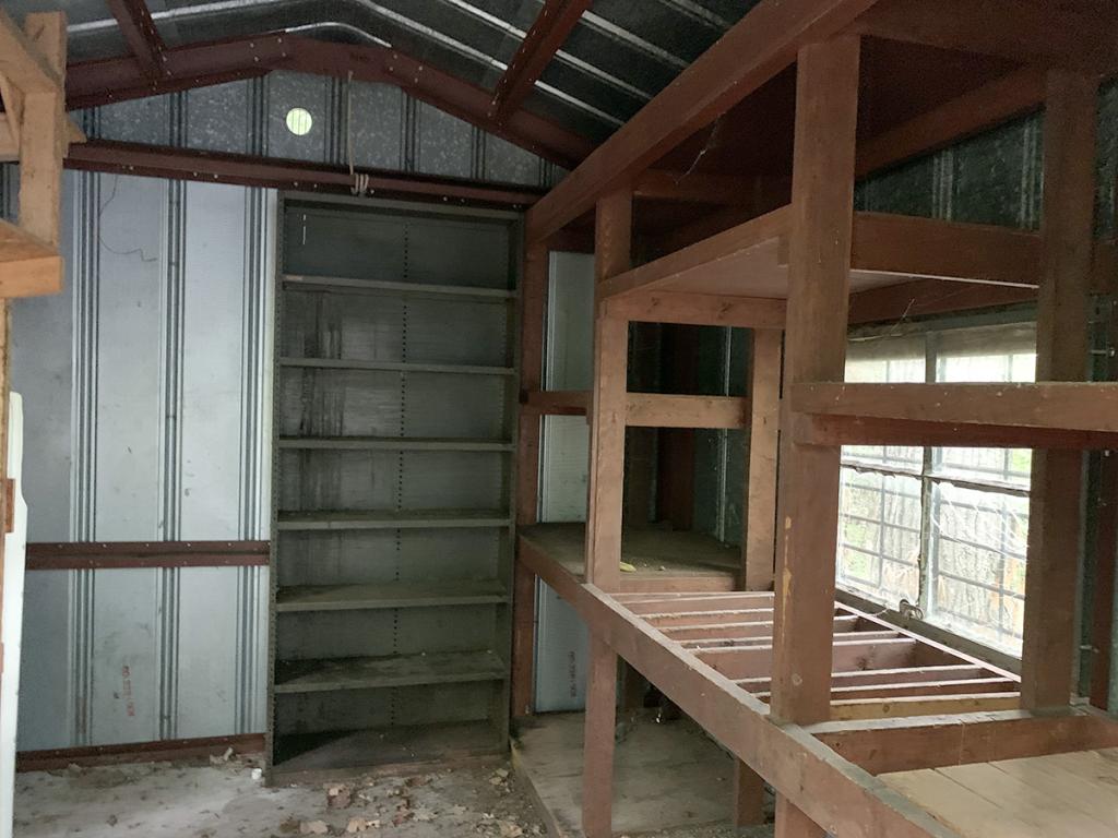 Unfinished room with metal paneling, ceiling and built-in shelves, and wooden shelves along one side